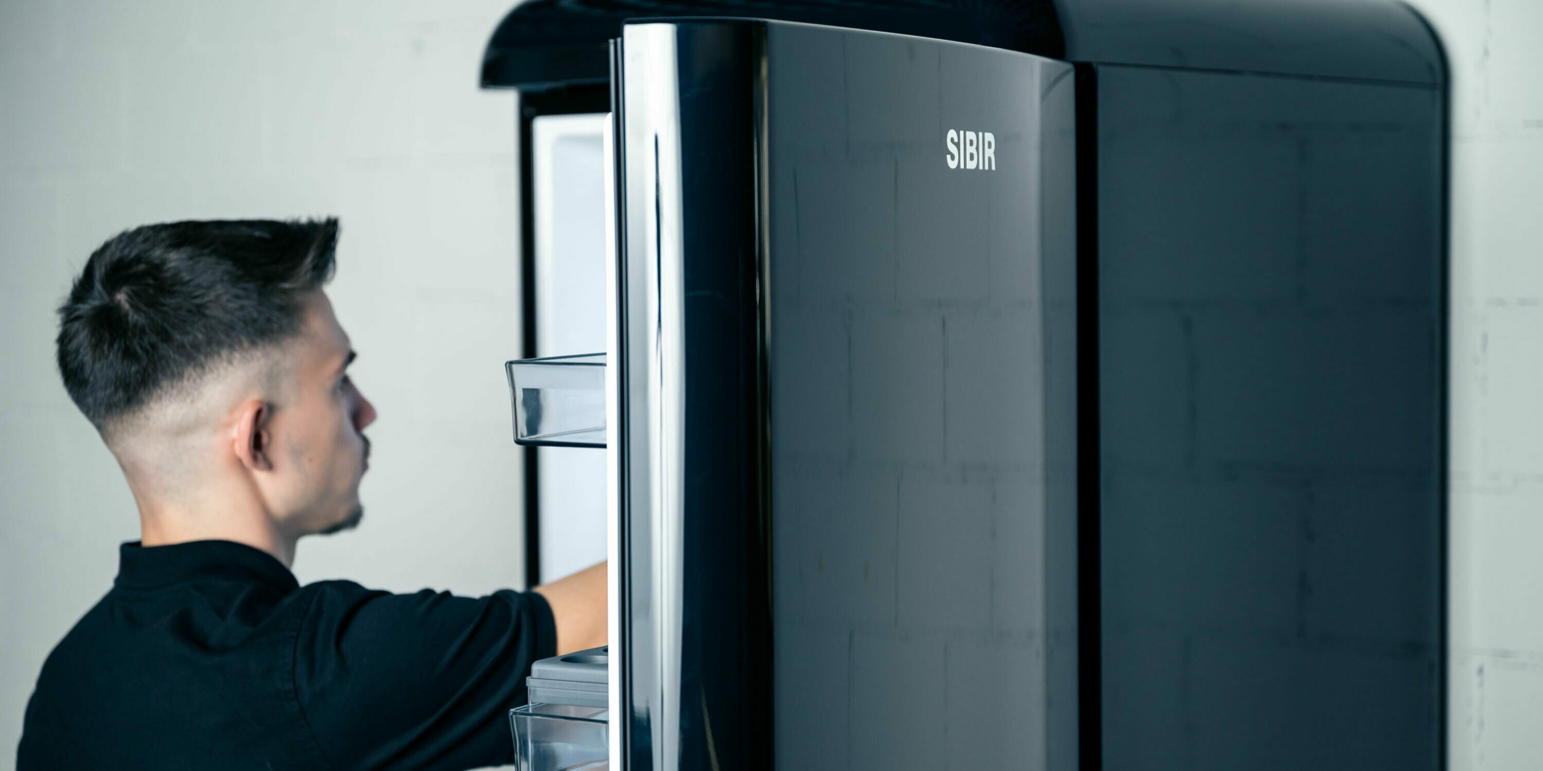 Person reaches into the black vintage fridge