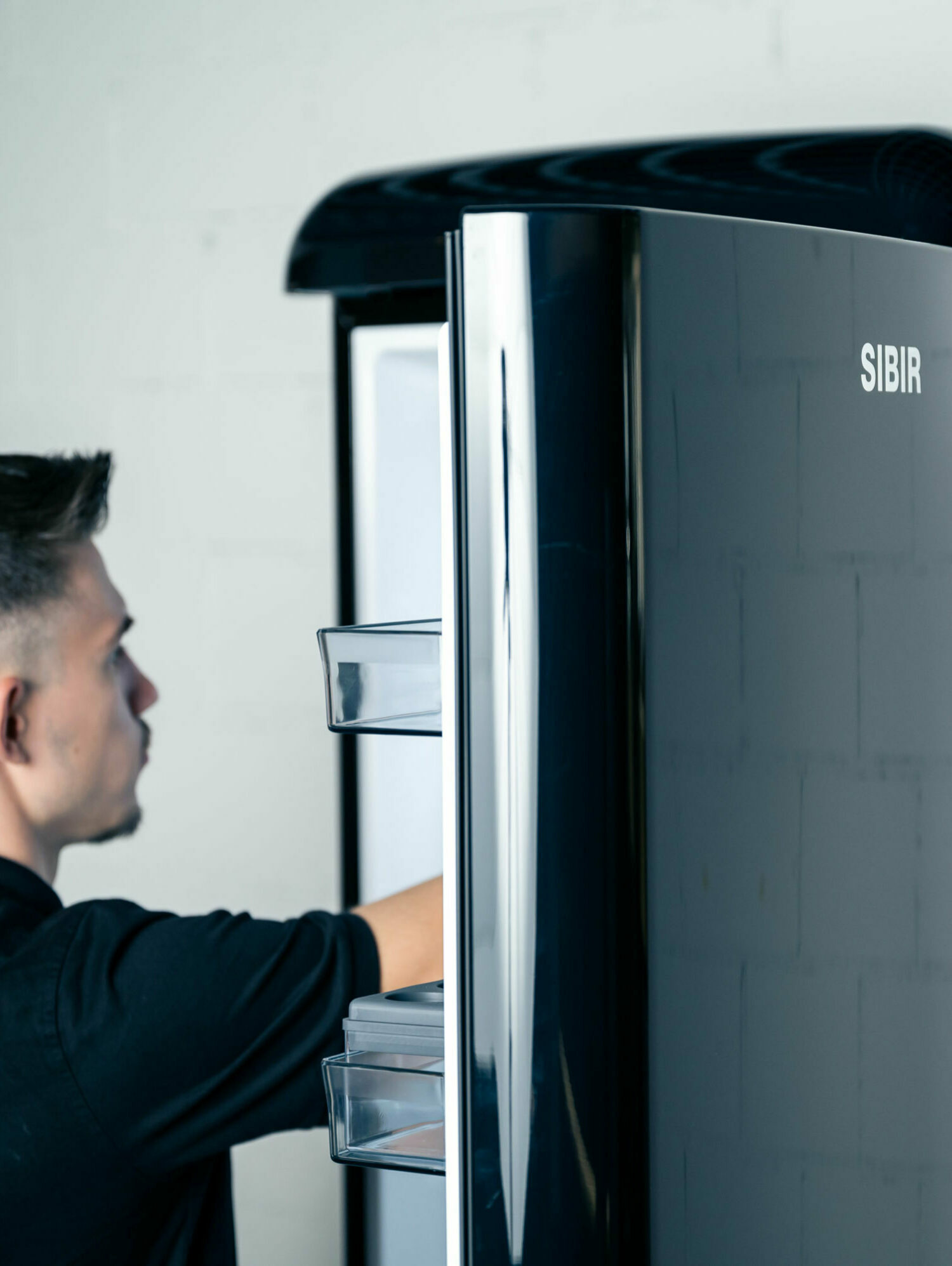 Person reaches into the black vintage fridge