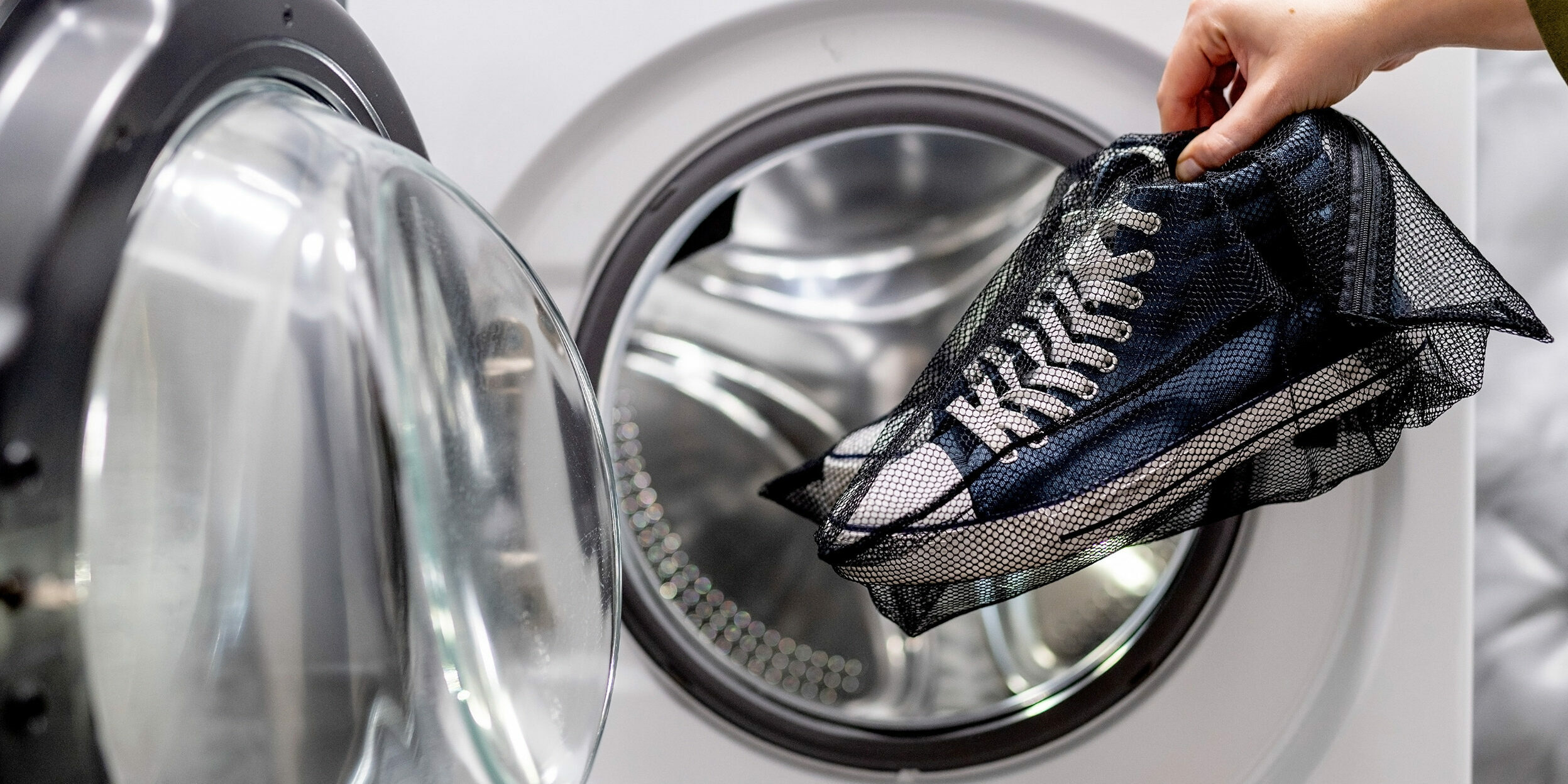 Weisse Sneaker in einem Wäschesack bereit für die Waschmaschine